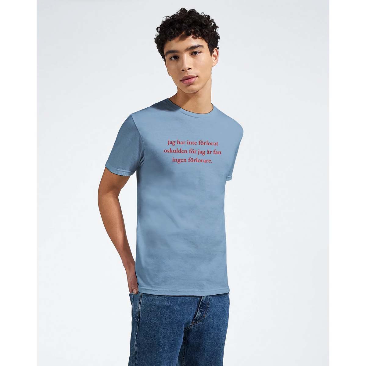 Ljusblå t-shirt med röd texttryck, bärs av modell
